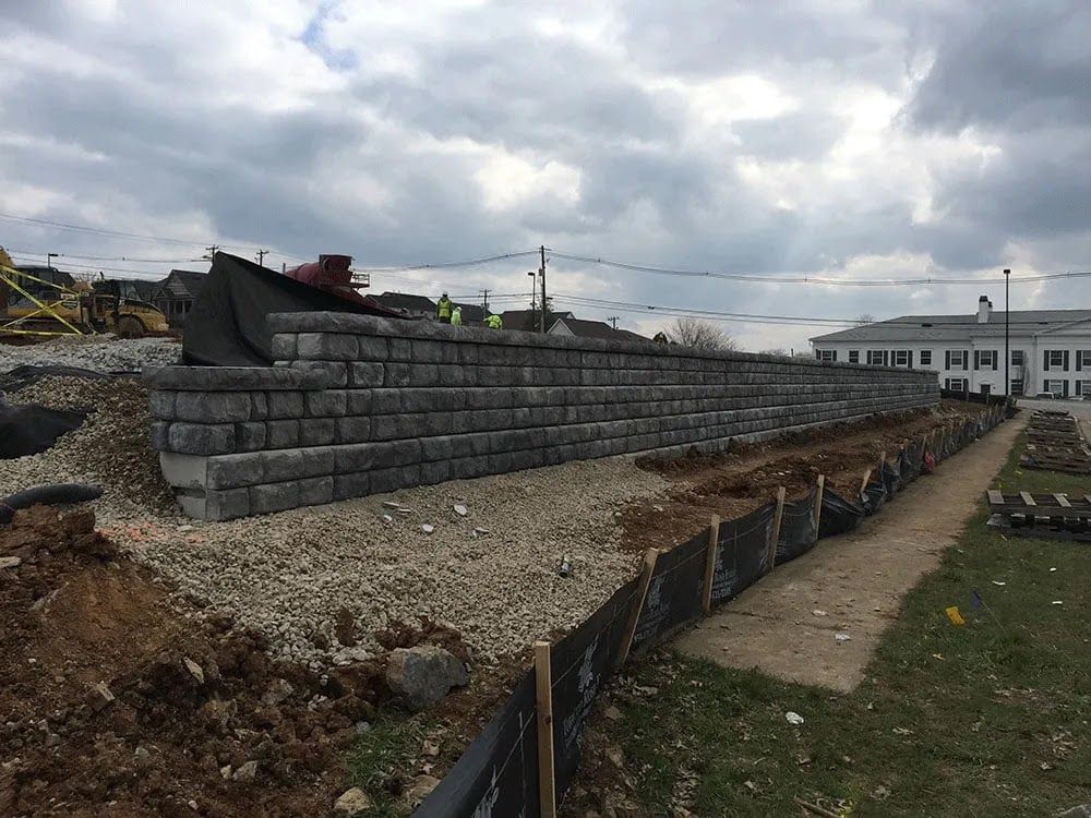 A large brick wall is being built in a field.