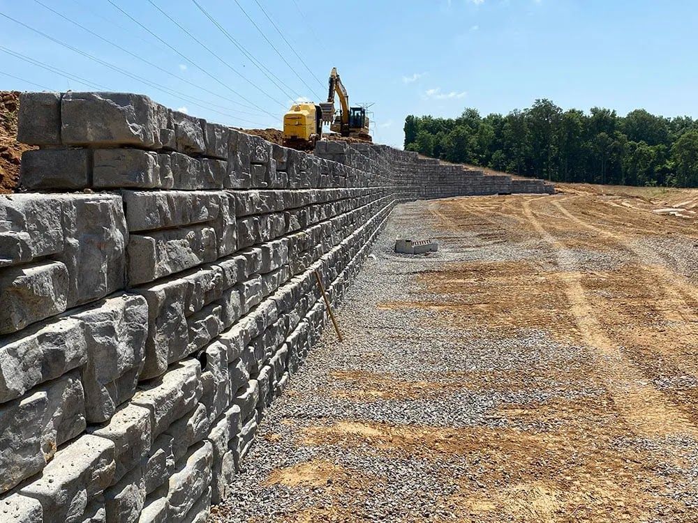 A large stone wall is being built on top of a dirt field.
