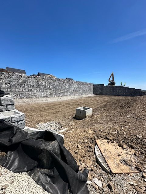 A large stone wall is being built in the middle of a dirt field.