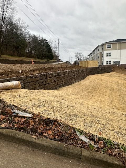 A brick wall is being built in front of a house under construction.