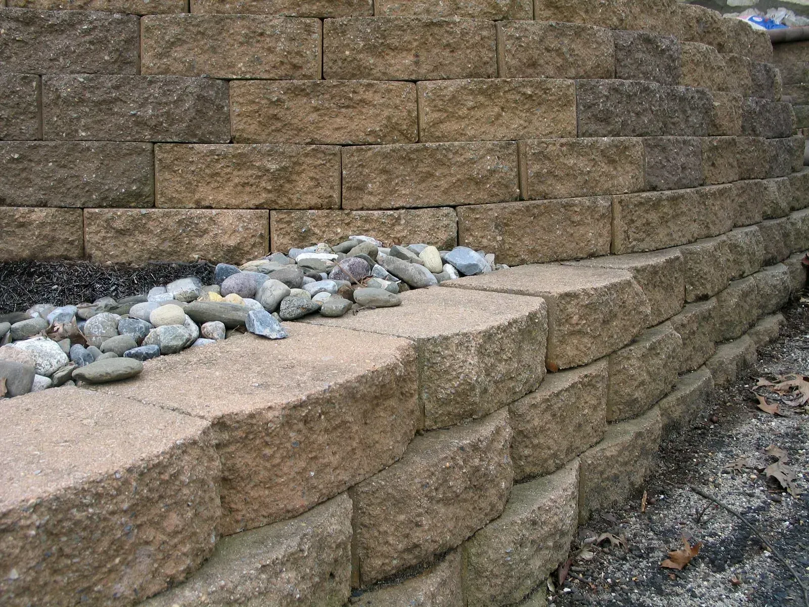A pile of rocks is sitting on the side of a brick wall.