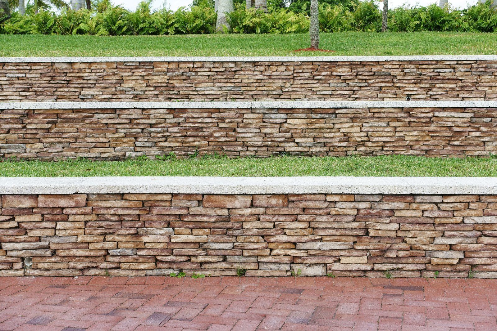 A stone wall with steps leading up to a grassy hill.