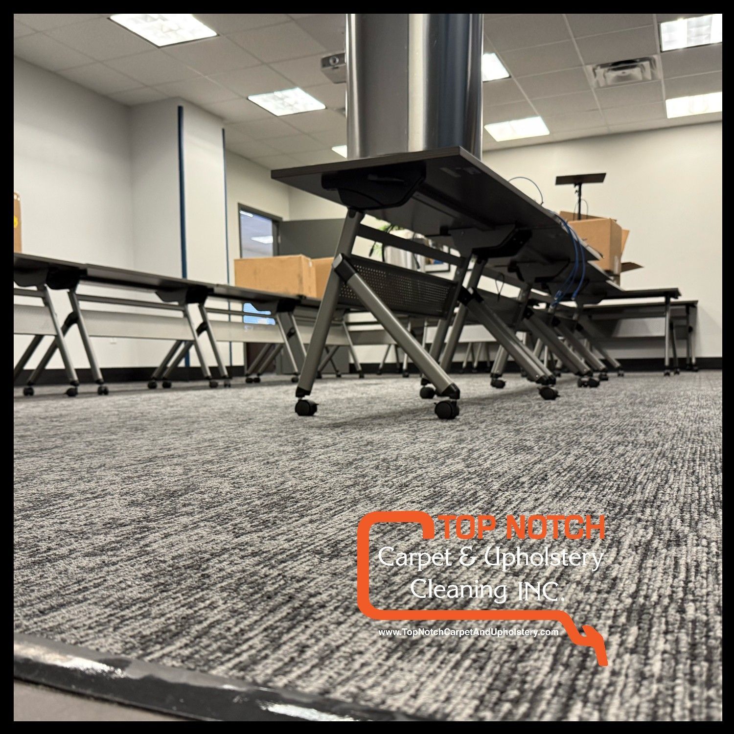 Gray office carpet with foldable tables and cardboard boxes.