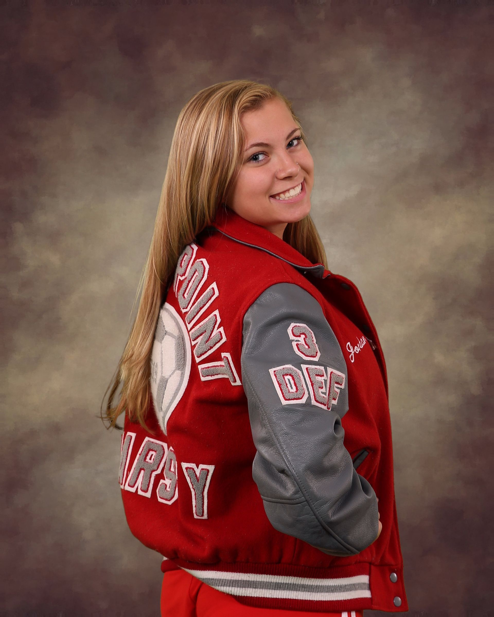 A girl wearing a red varsity jacket with gray sleeves