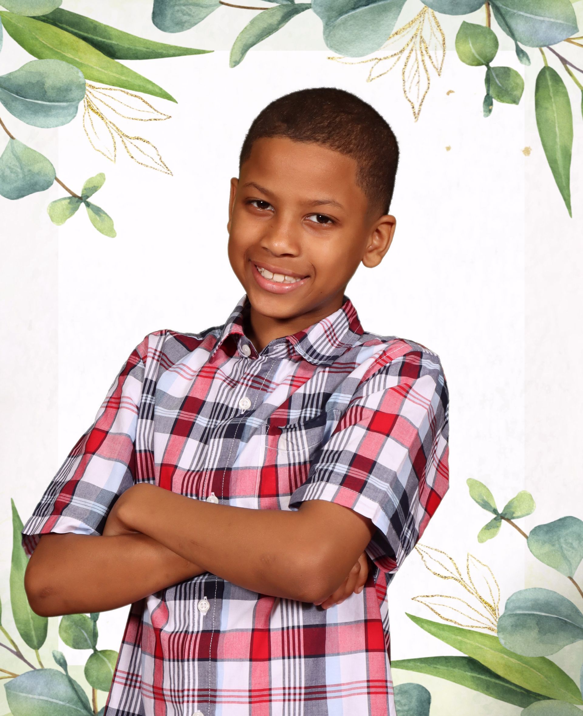 A young boy in a plaid shirt is posing for a picture with his arms crossed.