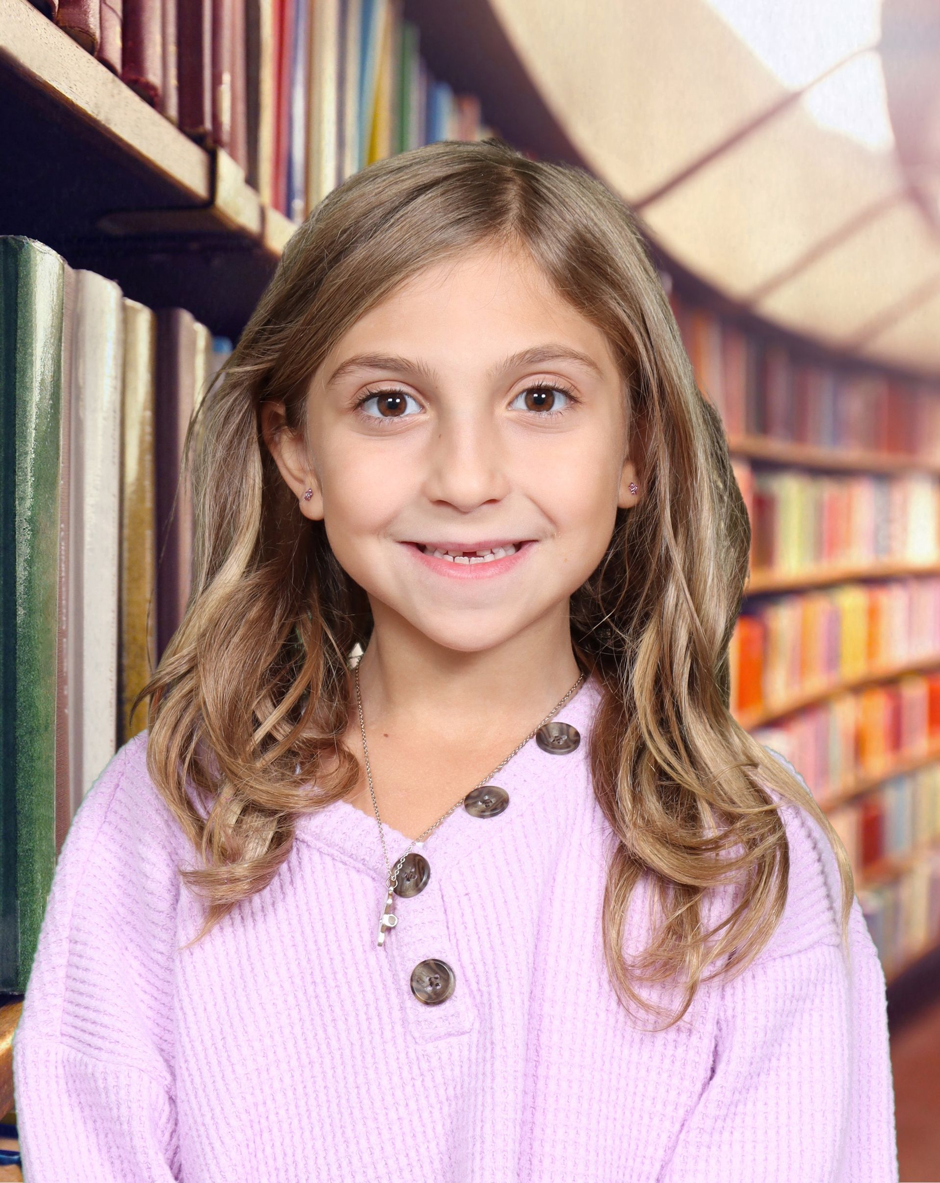A young girl in a purple sweater is smiling in front of a library.
