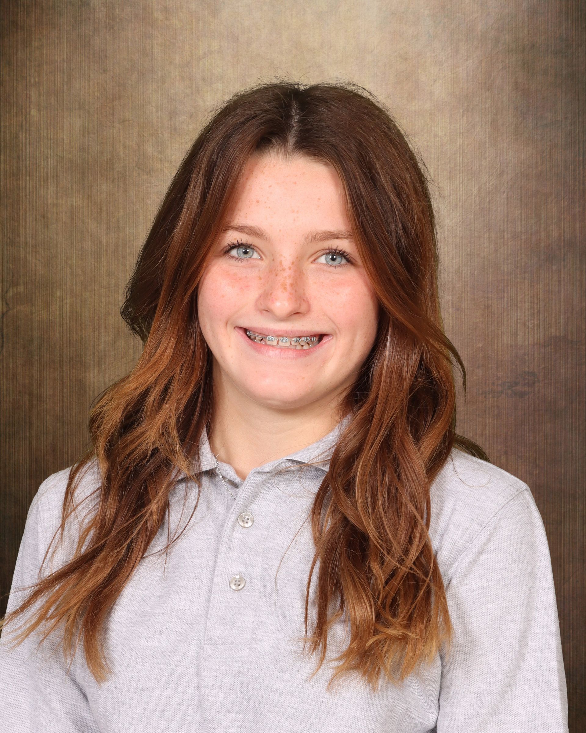 A young girl with braces on her teeth is smiling for a picture.