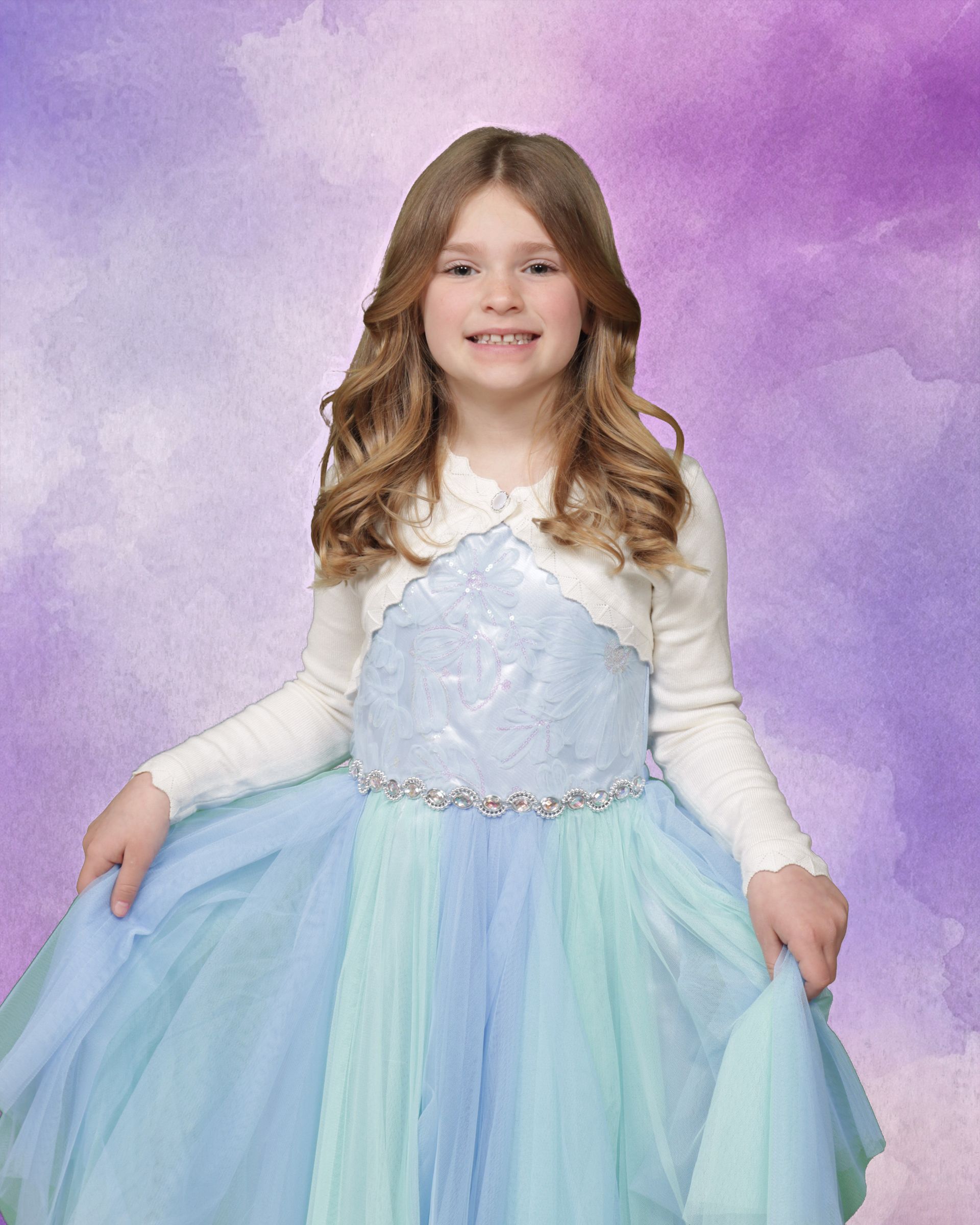 A young girl in a blue and green dress is standing in front of a purple background.