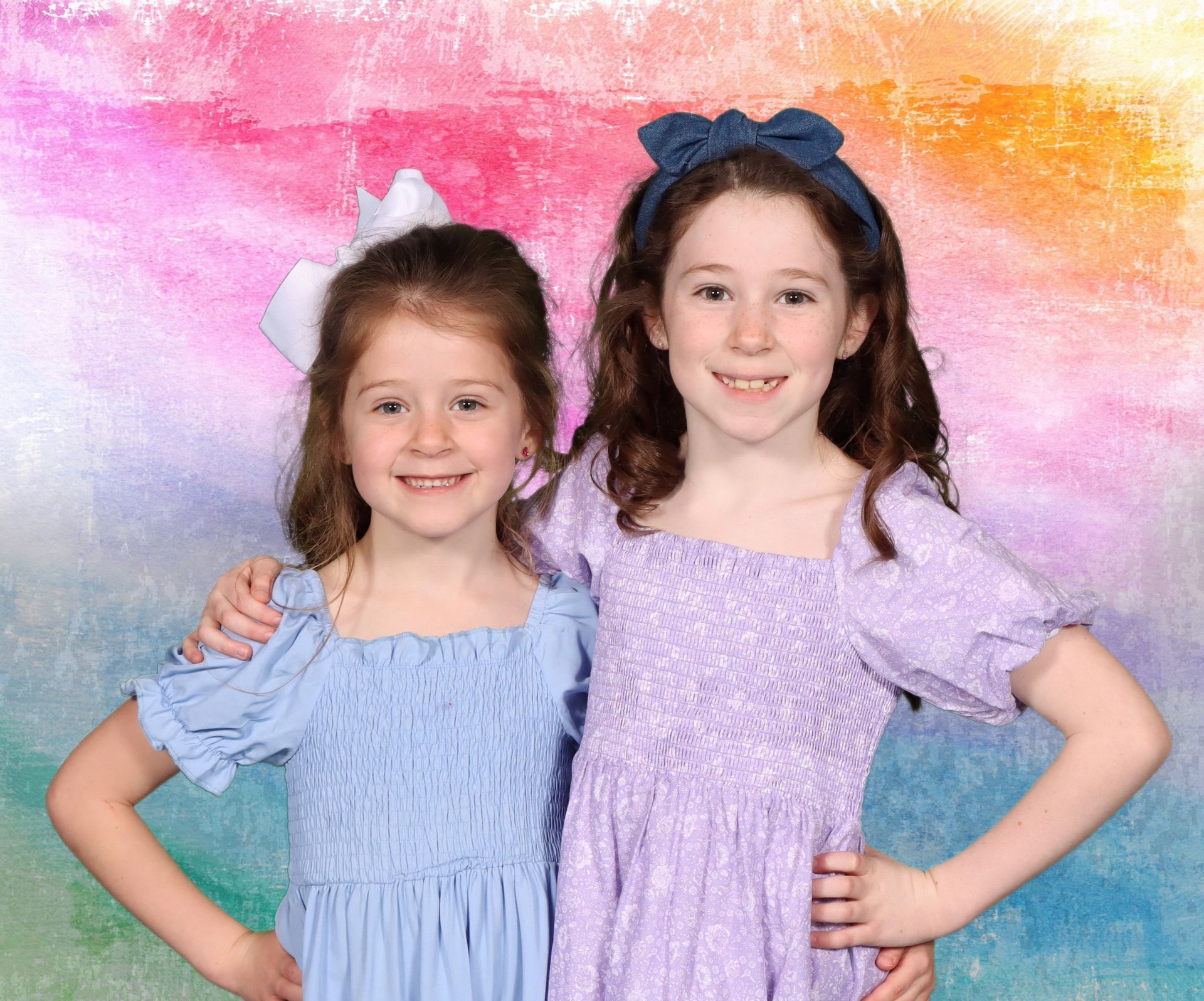 Two little girls posing for a picture with a rainbow background
