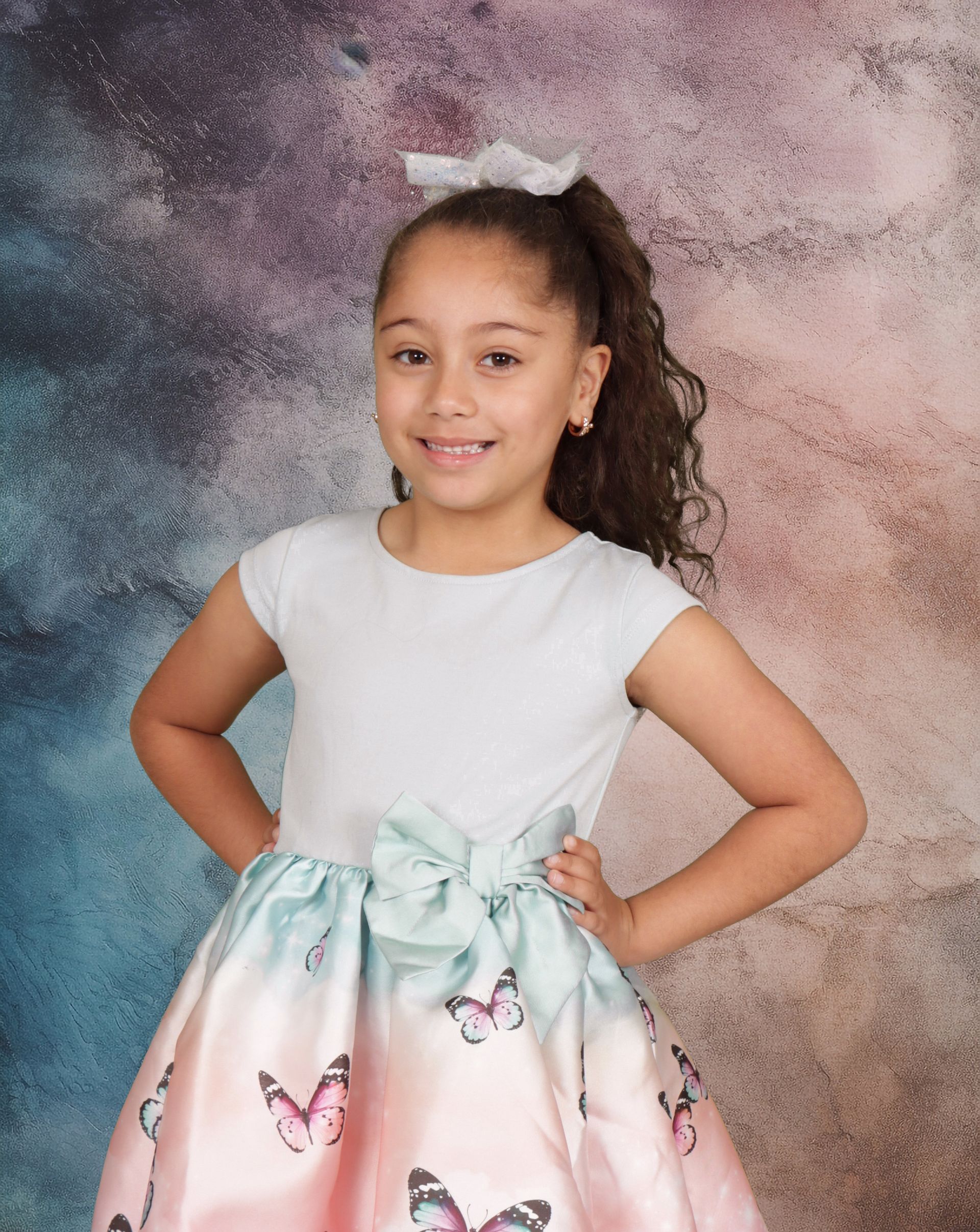 A little girl is wearing a dress with butterflies on it.