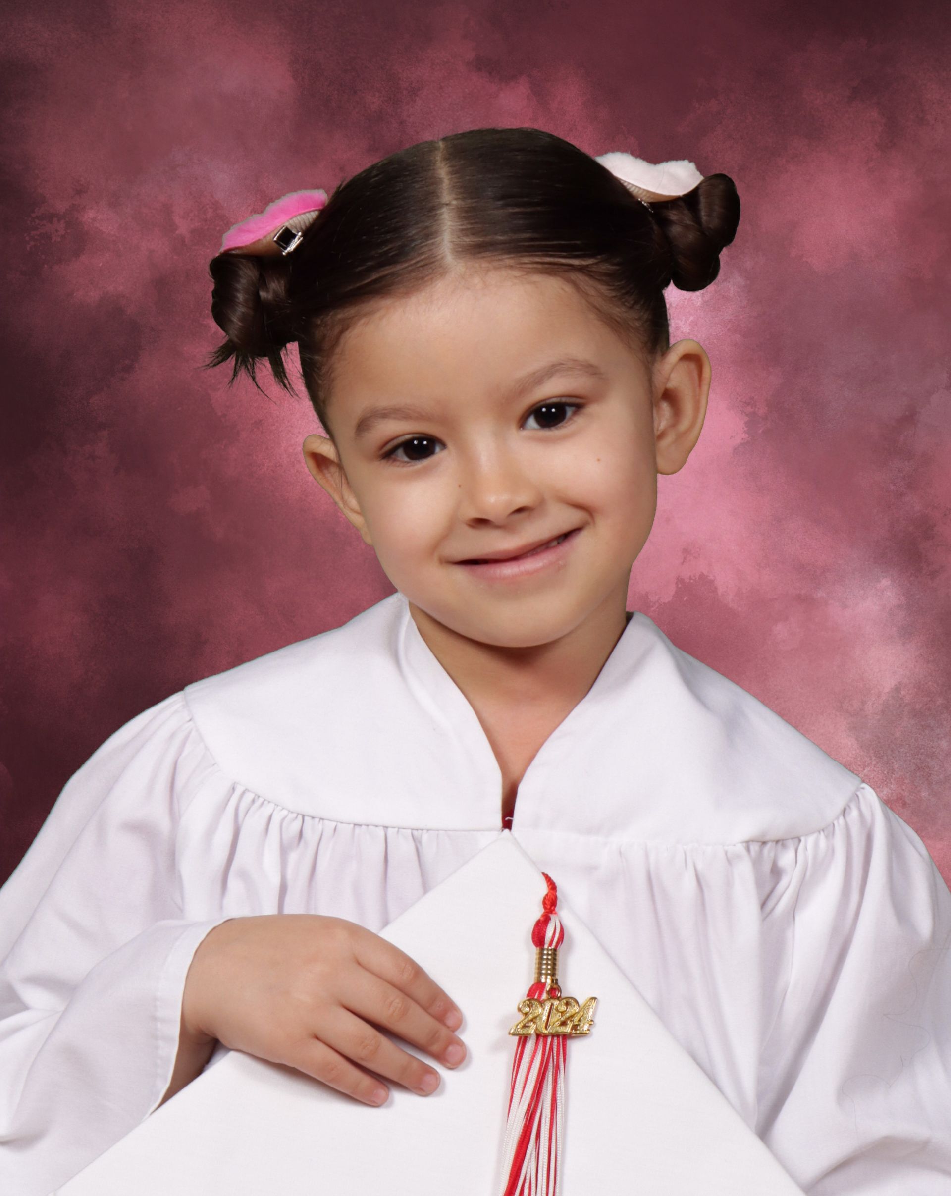 A little girl in a white gown is holding a diploma