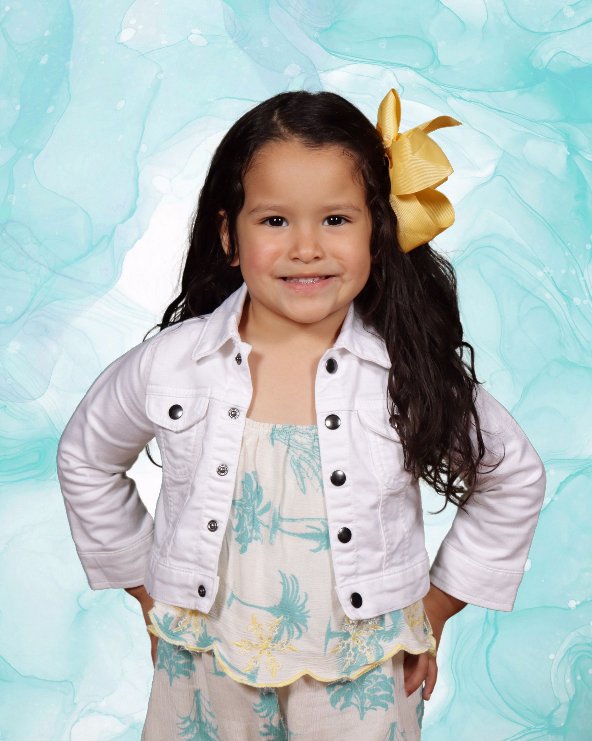 A little girl wearing a white jacket and a yellow bow in her hair