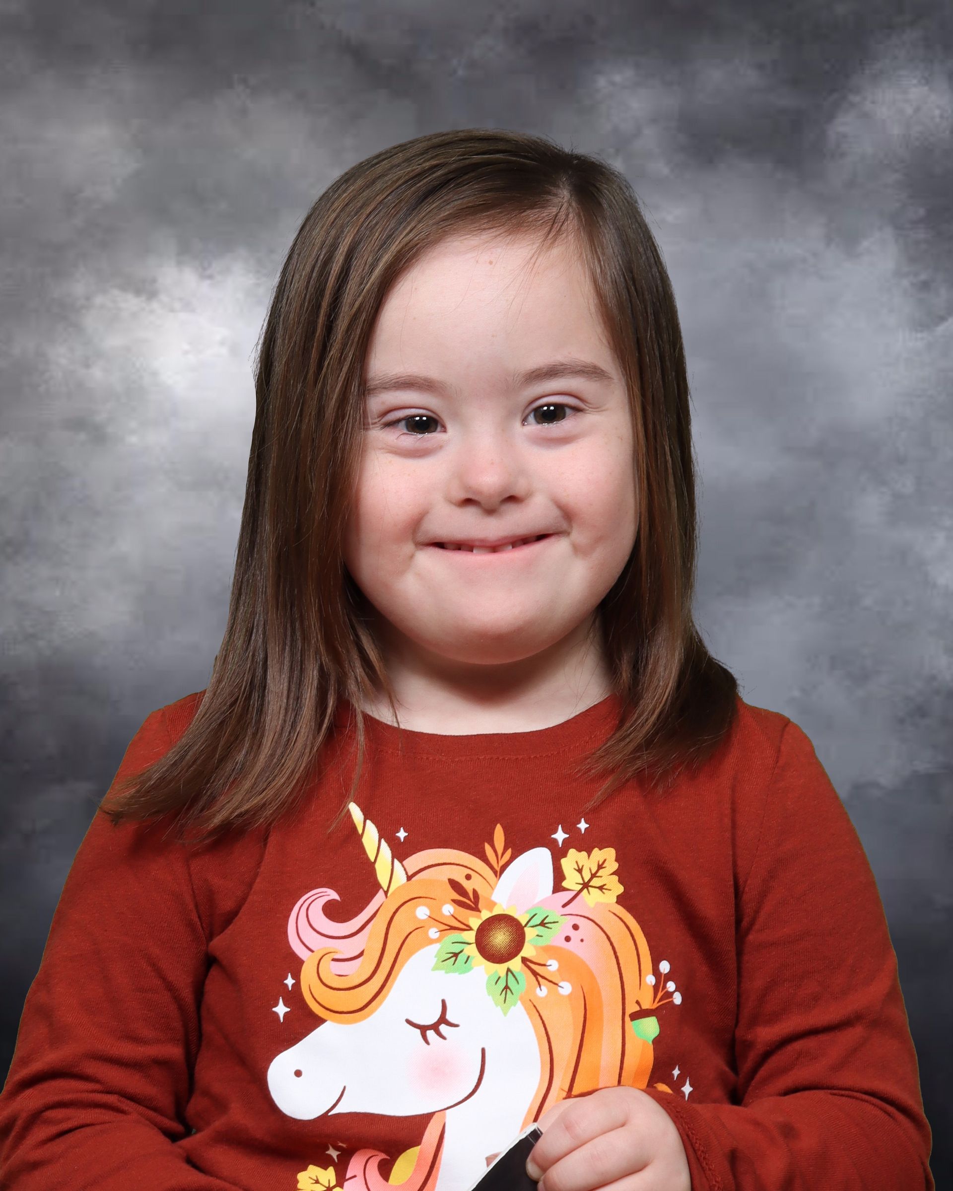 A little girl wearing a red shirt with a unicorn on it
