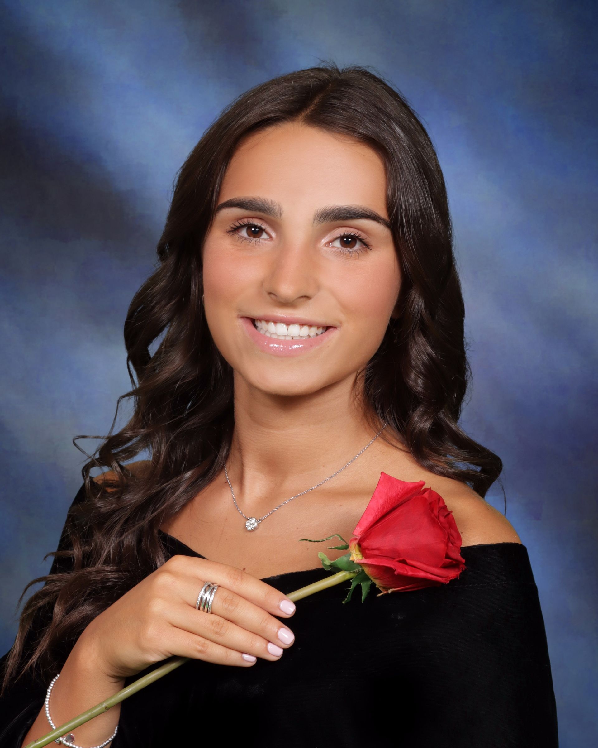A woman is holding a red rose in her hand and smiling.