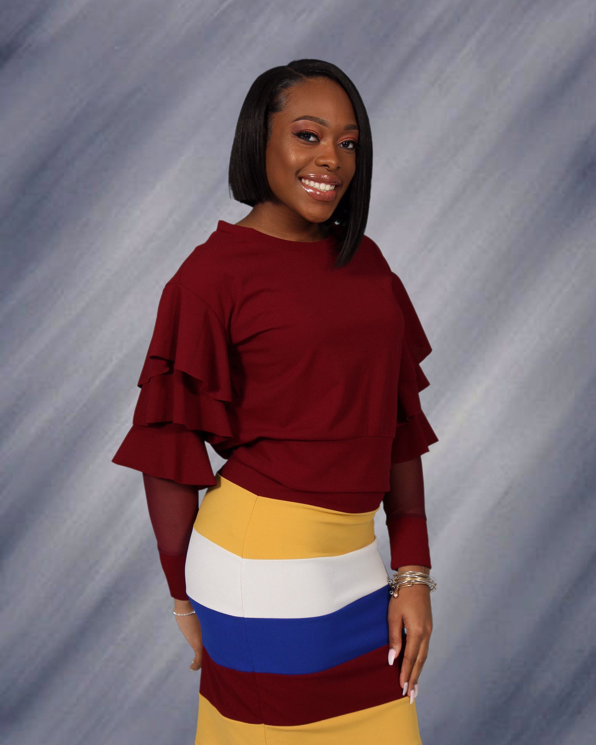 A woman is wearing a red sweater and a striped skirt.