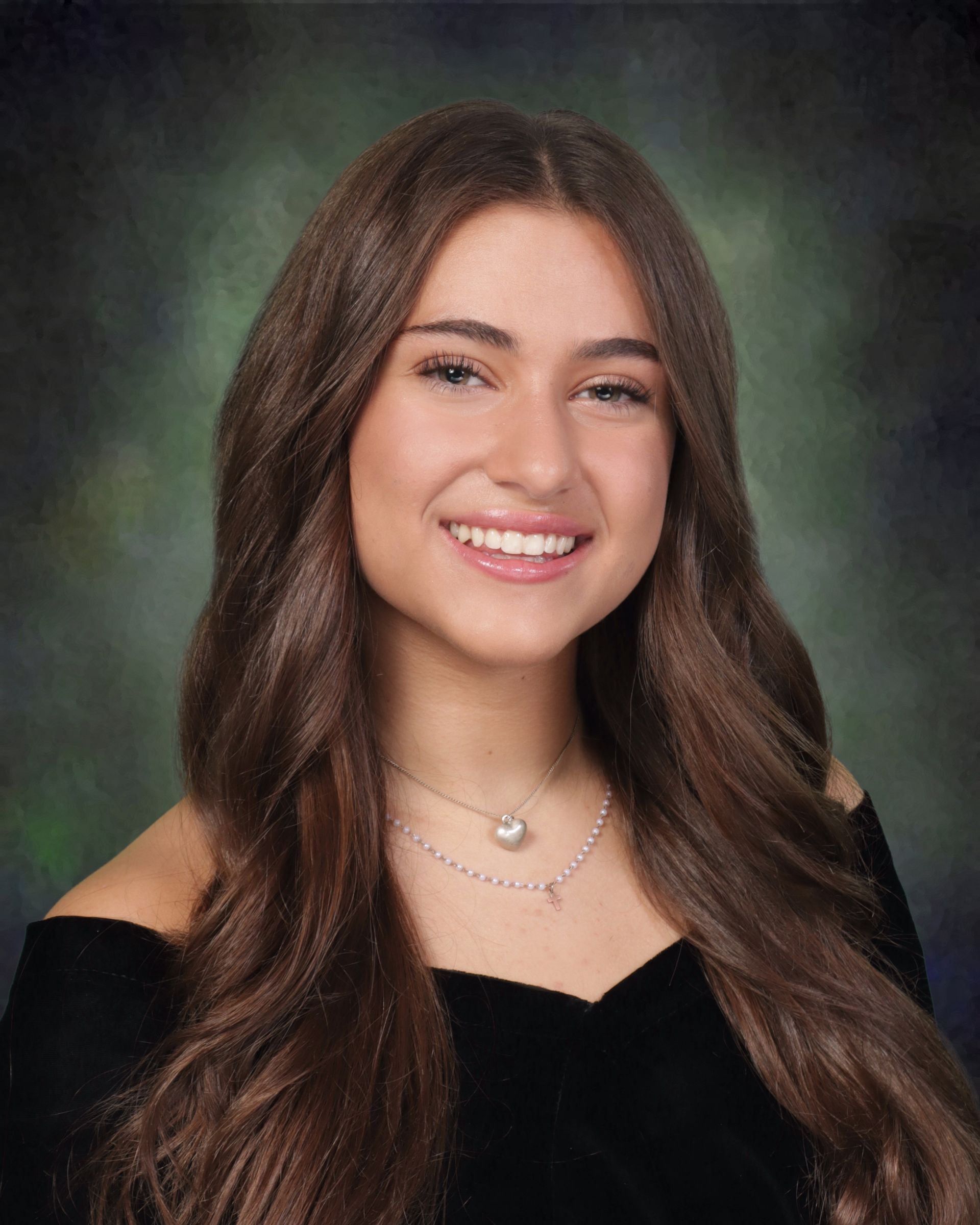 A young woman with long brown hair and a necklace is smiling for the camera.