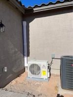 Outdoor AC units on a concrete pad next to a building with a downspout.