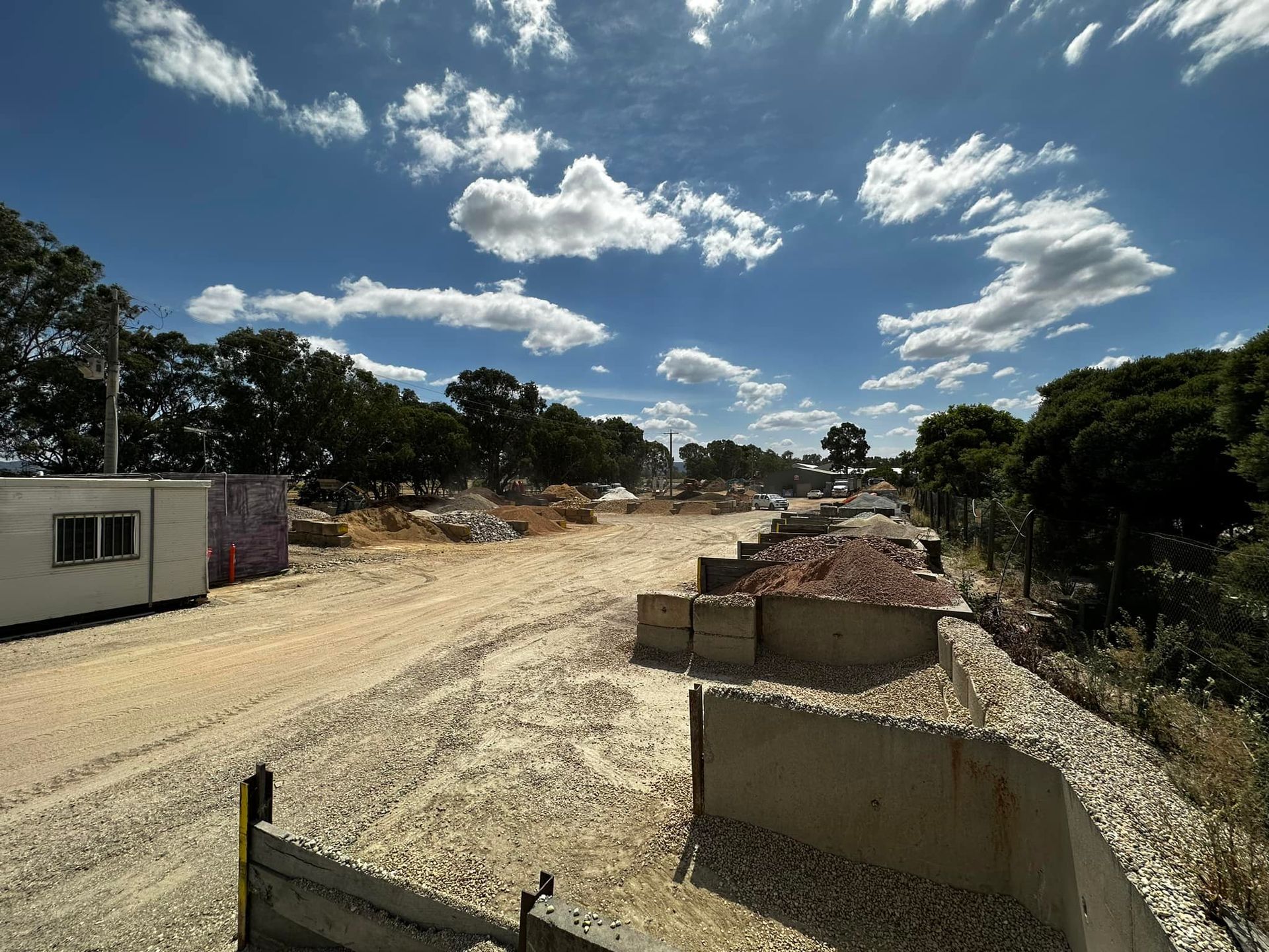 Construction site with dirt road, concrete barriers, and blue sky with clouds — Wodonga Sand & Soil in Wodonga, VIC