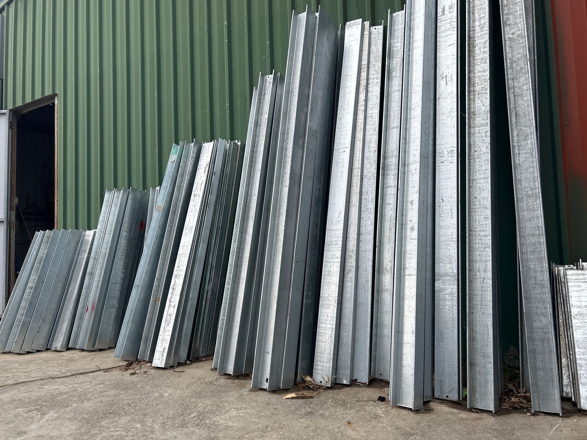 Stack of galvanized steel channel posts against a green building. — Wodonga Sand & Soil in Wodonga, VIC