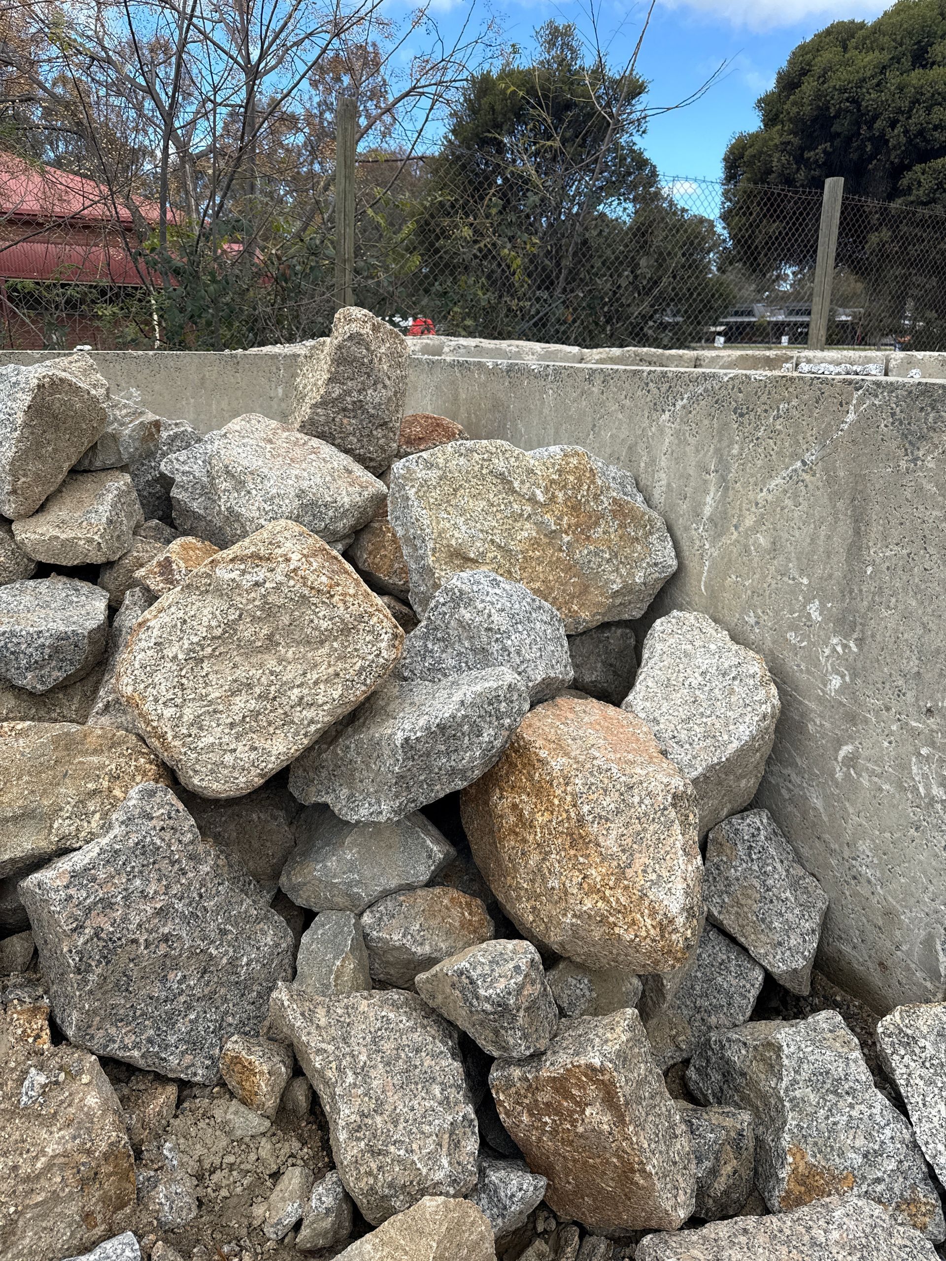 Pile Of Granite Rocks In Front Of A Concrete Structure. The Rocks Vary In Color — Wodonga Sand & Soil in Wodonga, VIC