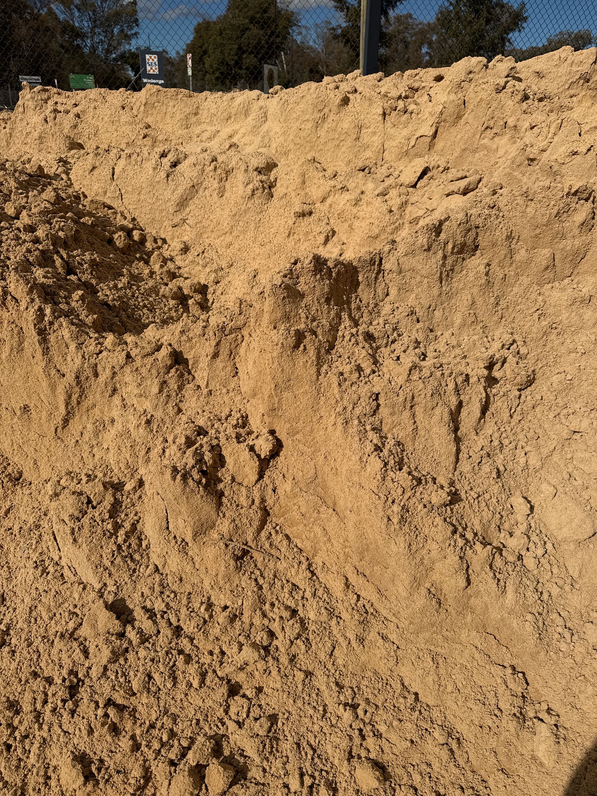 A large pile of tan sand with a rough, textured surface. Outdoors on a sunny day. — Wodonga Sand & Soil in Wodonga, VIC