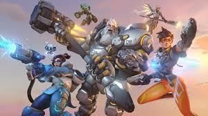 Overwatch characters Tracer, Reinhardt, Mei, Mercy, and Torbjörn in an action-oriented group pose against a sunset sky.