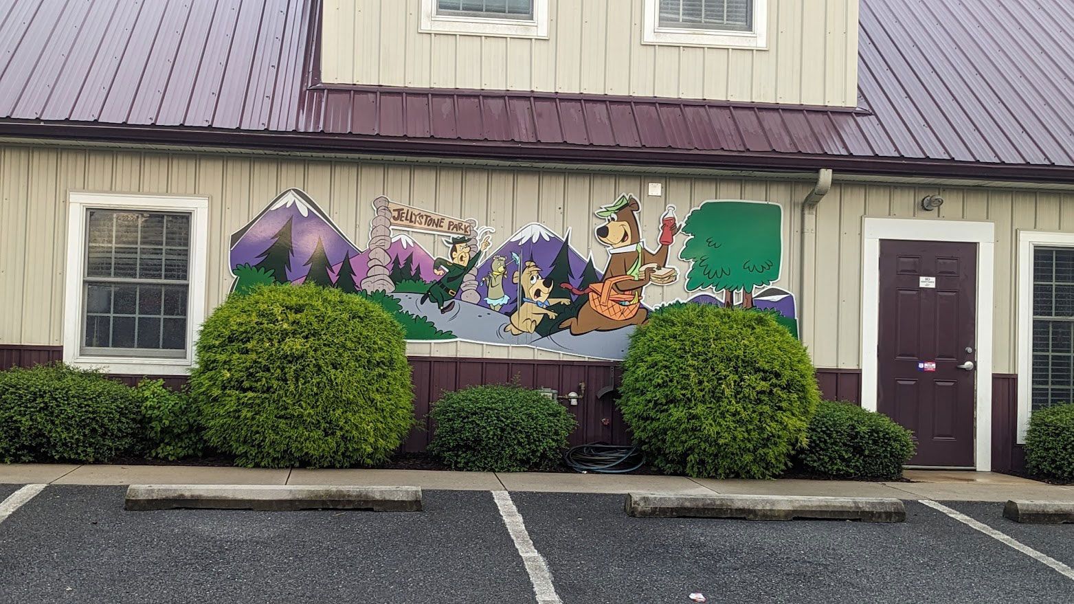 A colorful mural featuring Santa's sleigh, mountains, and trees painted on the tan exterior wall of a building.