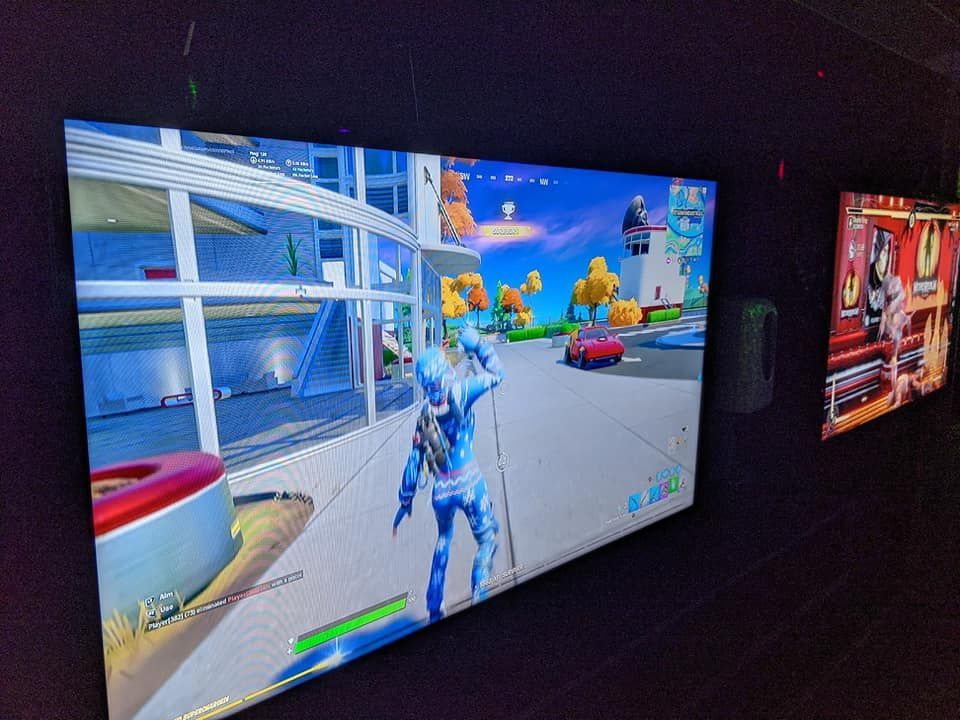 Two large screens displaying video games mounted on a dark wall.