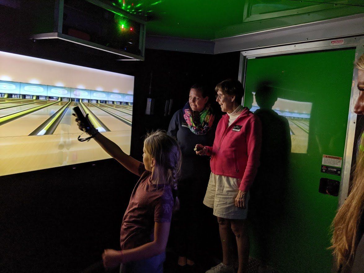 Group standing outdoors, two individuals holding bright green water guns near a table with a laptop.