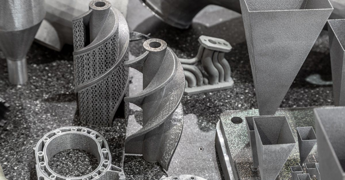 A collection of printed metal components sitting on a gray surface. The items are various shapes and sizes.