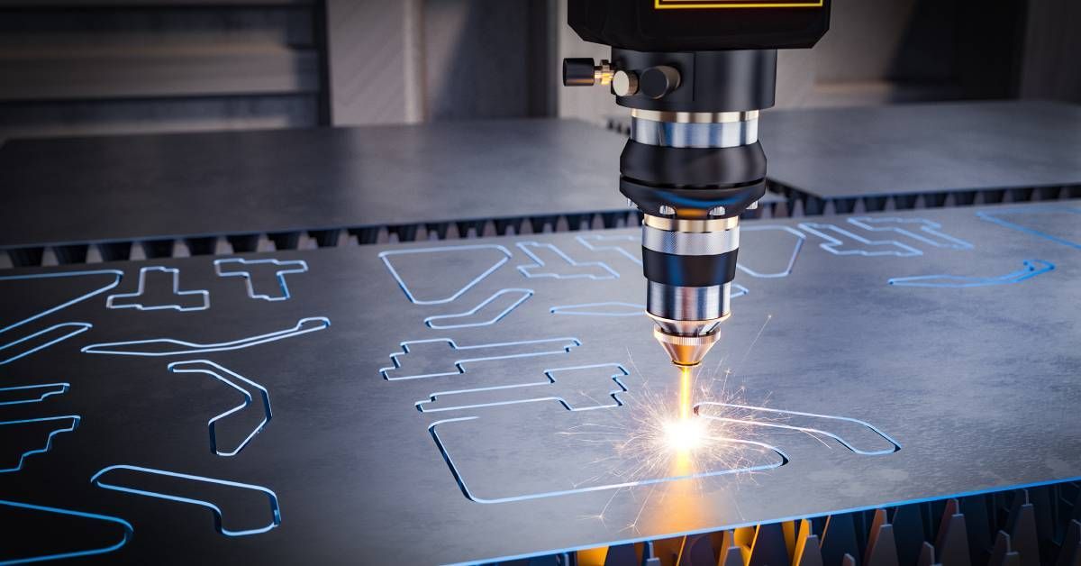 A laser cutting machine in the process of cutting various designs into a piece of sheet metal in a factory.