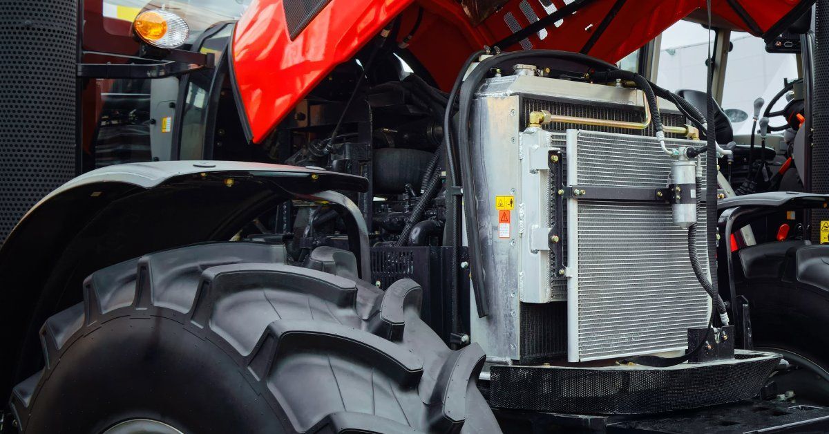 The engine and radiator are exposed under the open red hood of a large agricultural tractor.