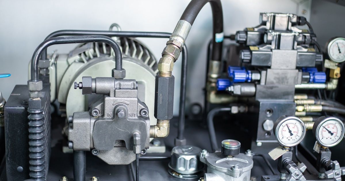 A hydraulic system that features a pump connected to a motor, several black tubes, and pressure gauges.