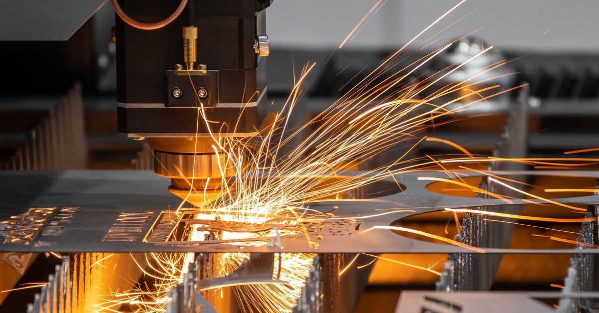 A close-up of an industrial metal fabrication tool cutting and removing material from metal.