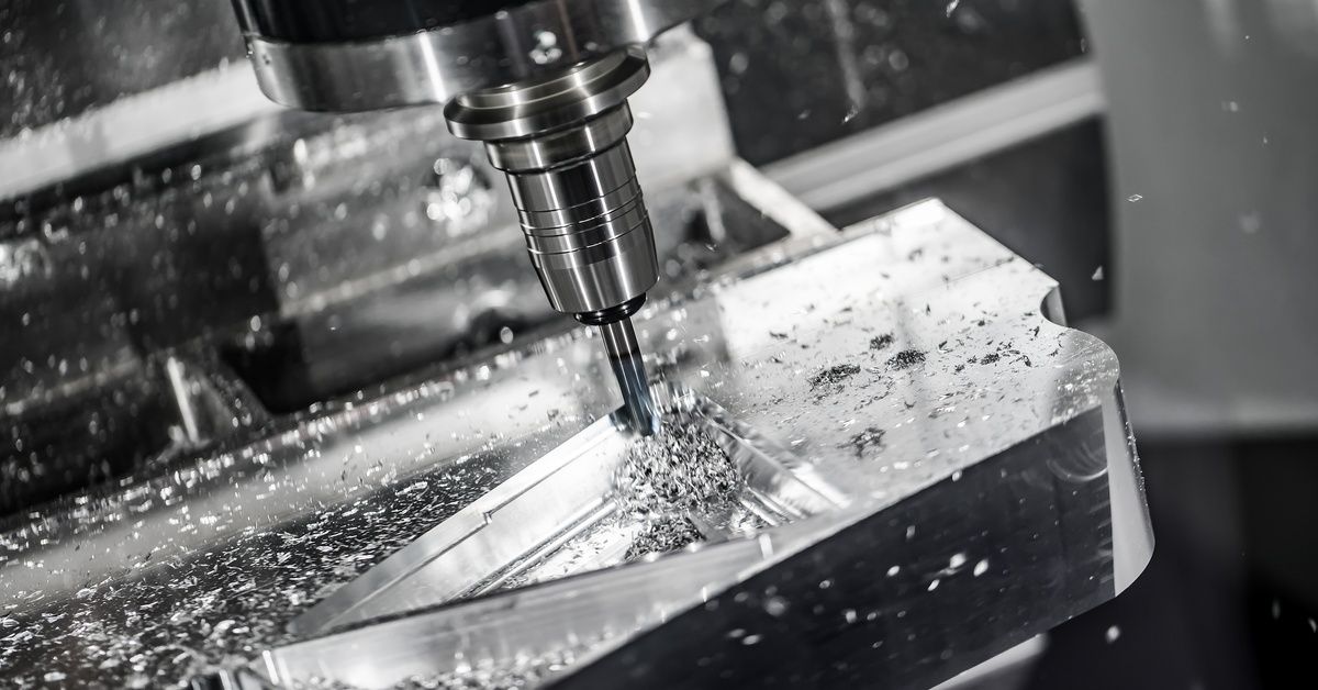 An angled close-up of a CNC milling machine removing material from a metal workpiece in a triangle.