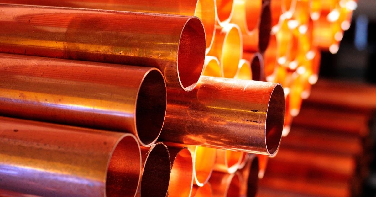 Several copper tubes are stacked on two shelves. One tube sticks outward from the rest of the tubes.