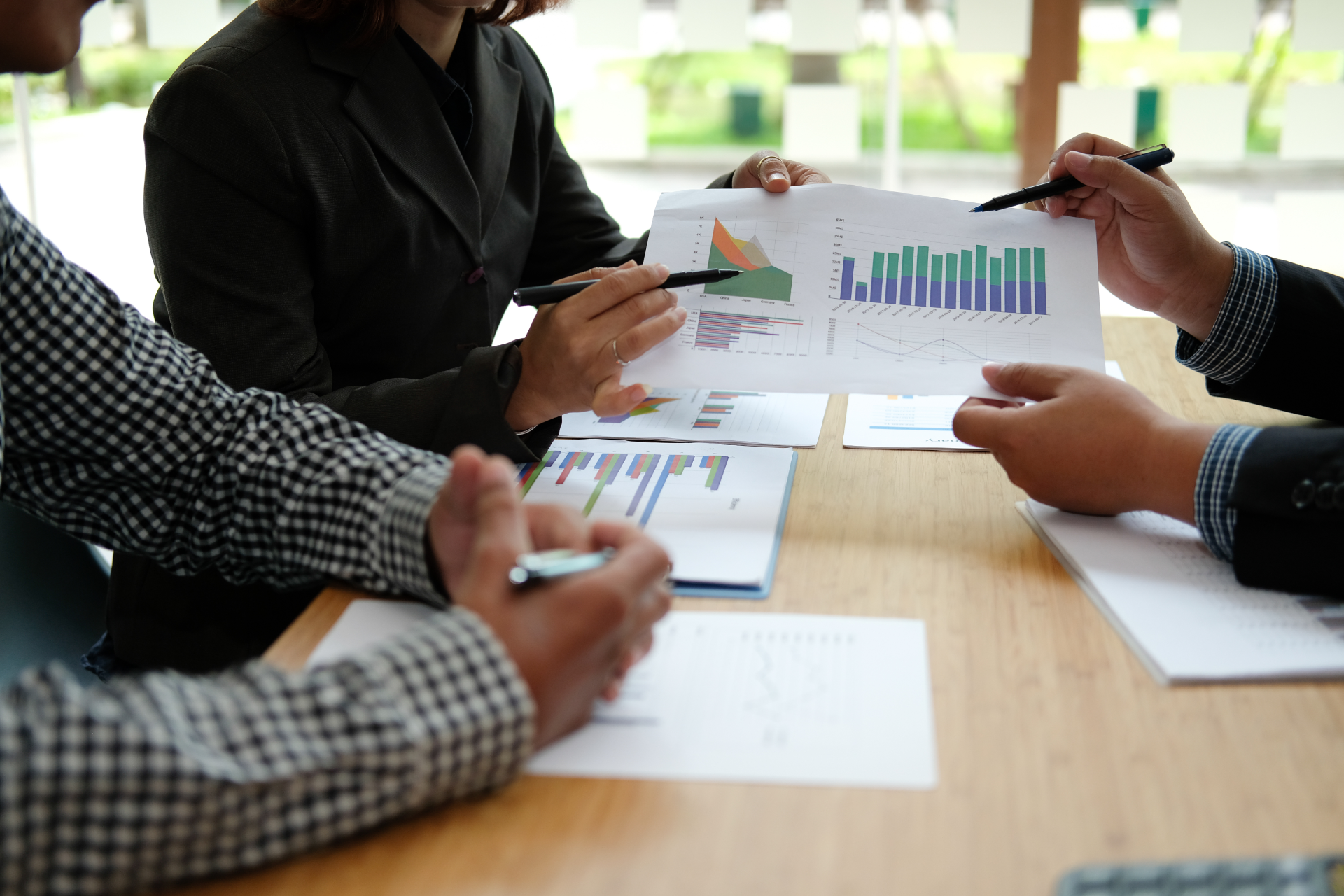 People in a meeting reviewing printed charts and graphs around a conference table