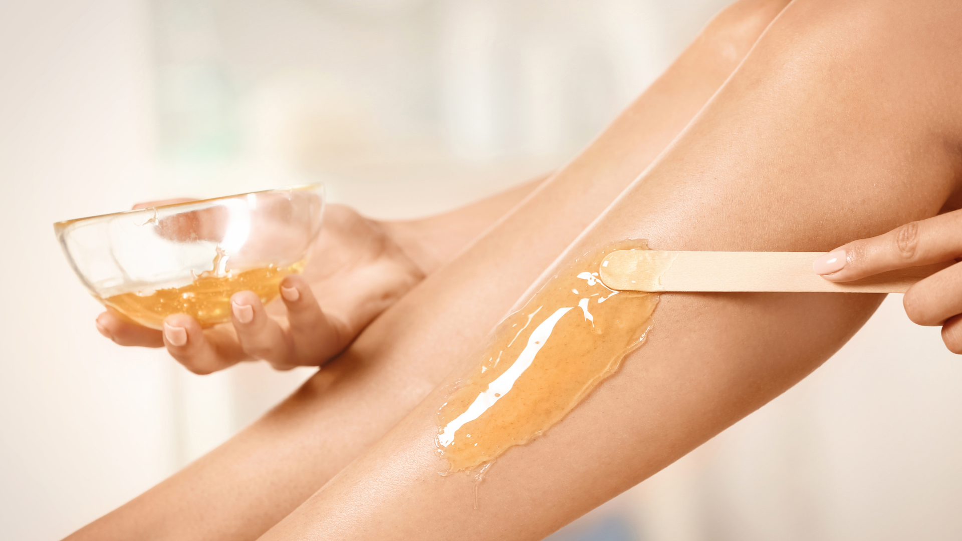 A woman is getting her legs waxed with a spatula.