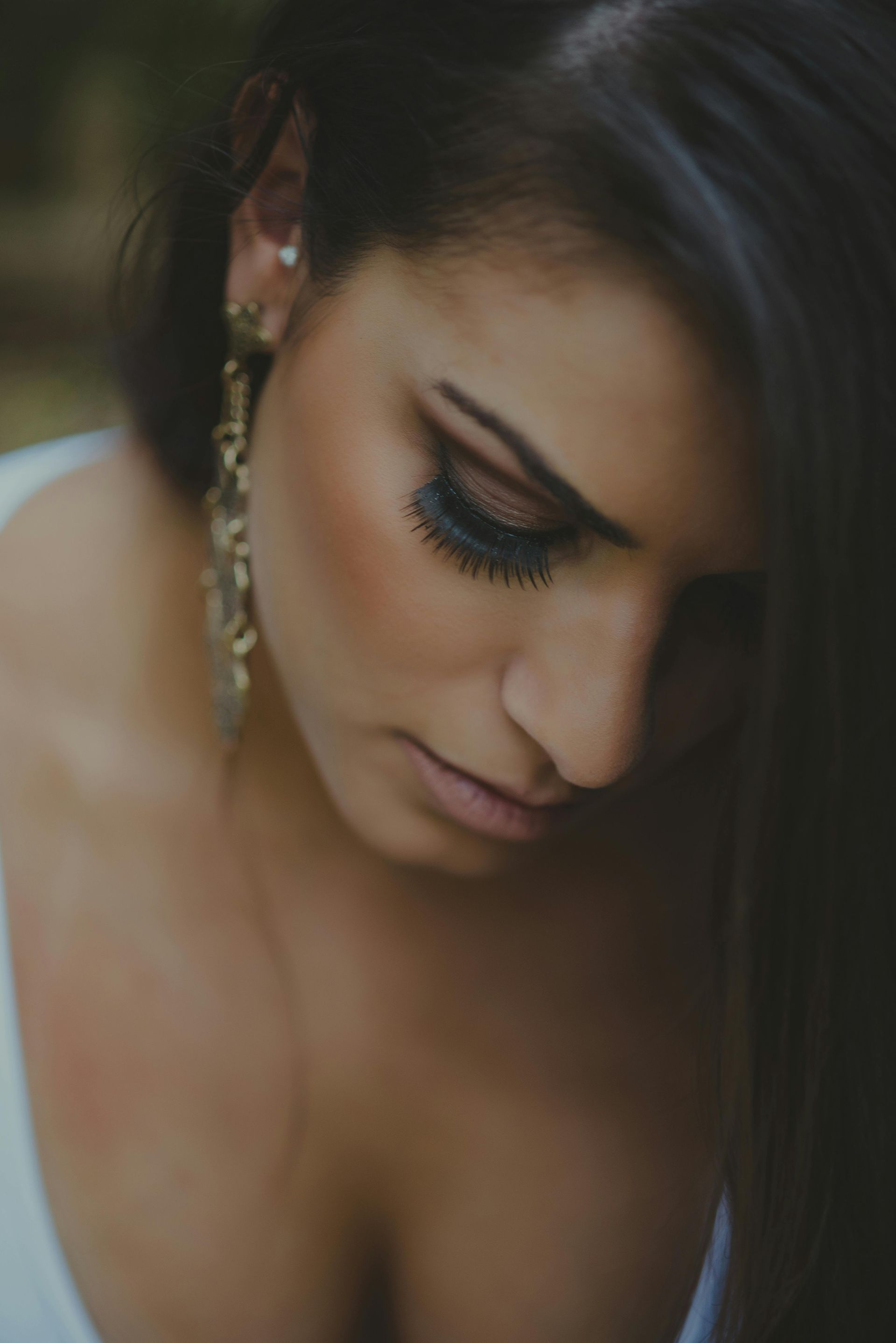 A close up of a woman wearing earrings and looking down.
