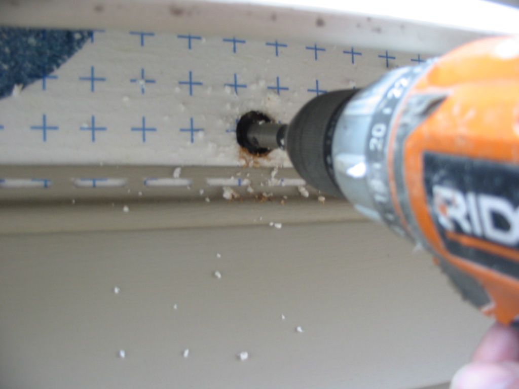 A person is using a ridgid drill to drill a hole in a piece of wood.