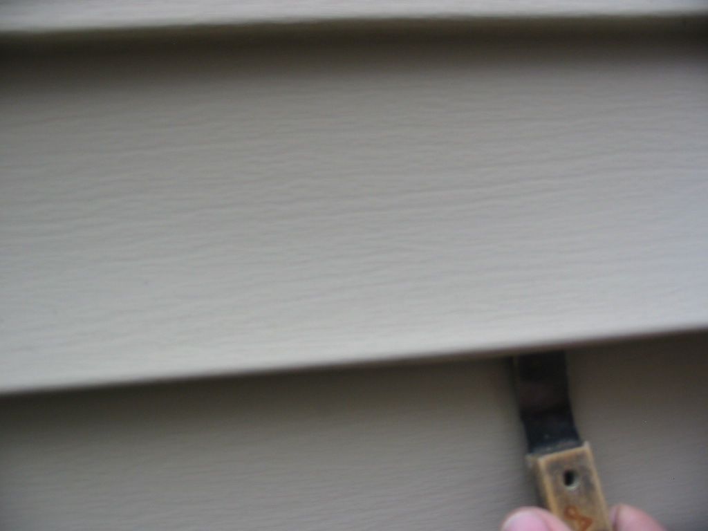 A person is painting a siding with a brush.
