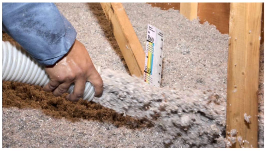A person is blowing insulation into the attic with a vacuum cleaner.