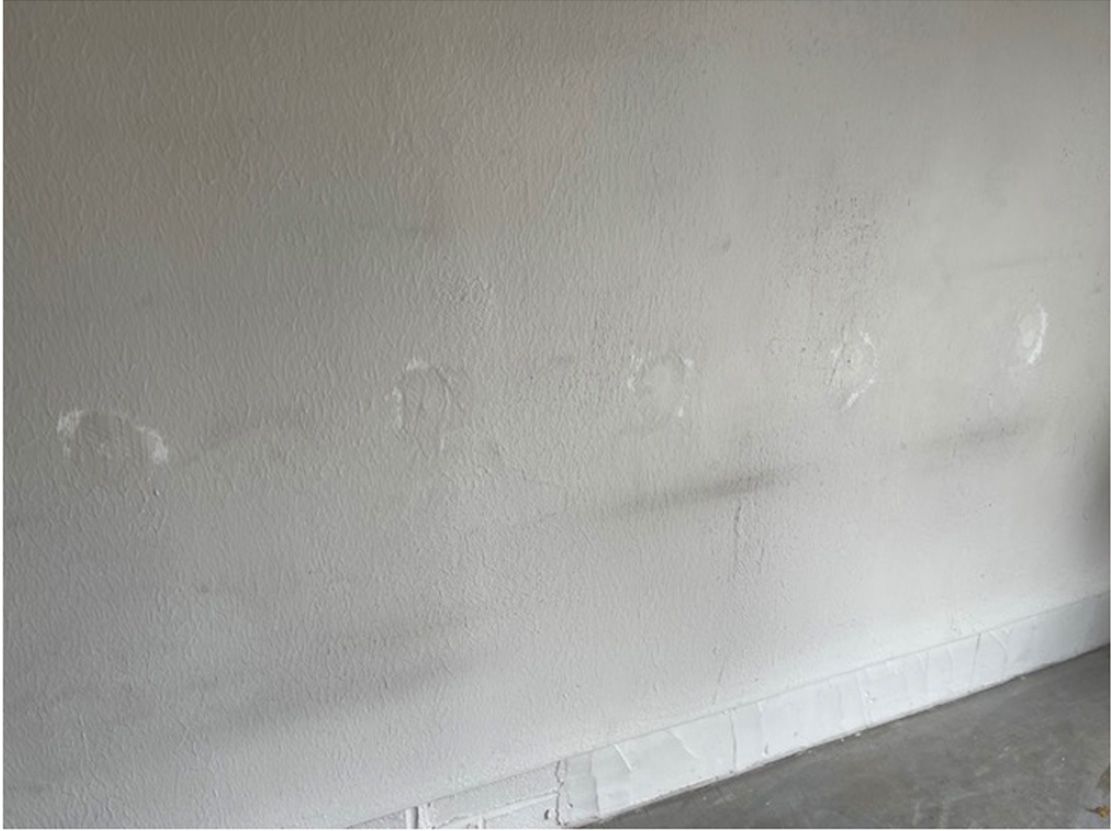 A white wall with a lot of stains on it in a room.