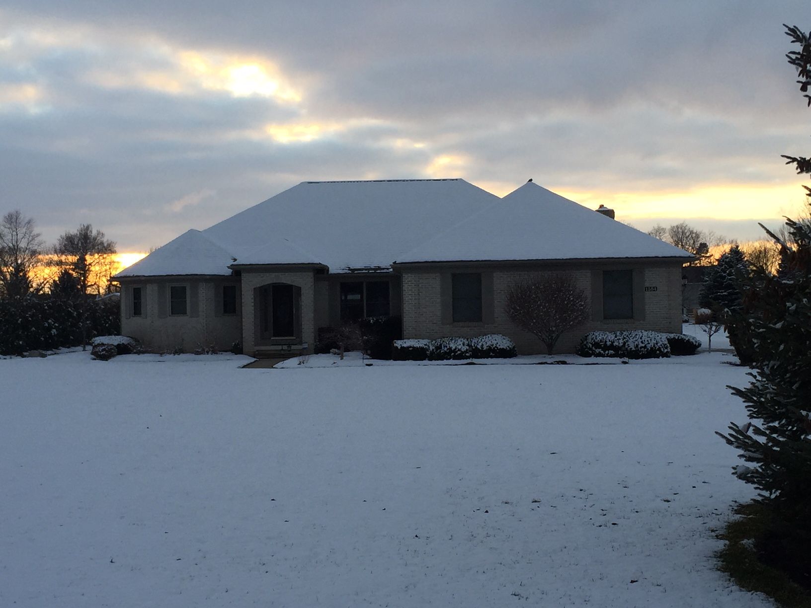 A house covered in snow with a sunset in the background