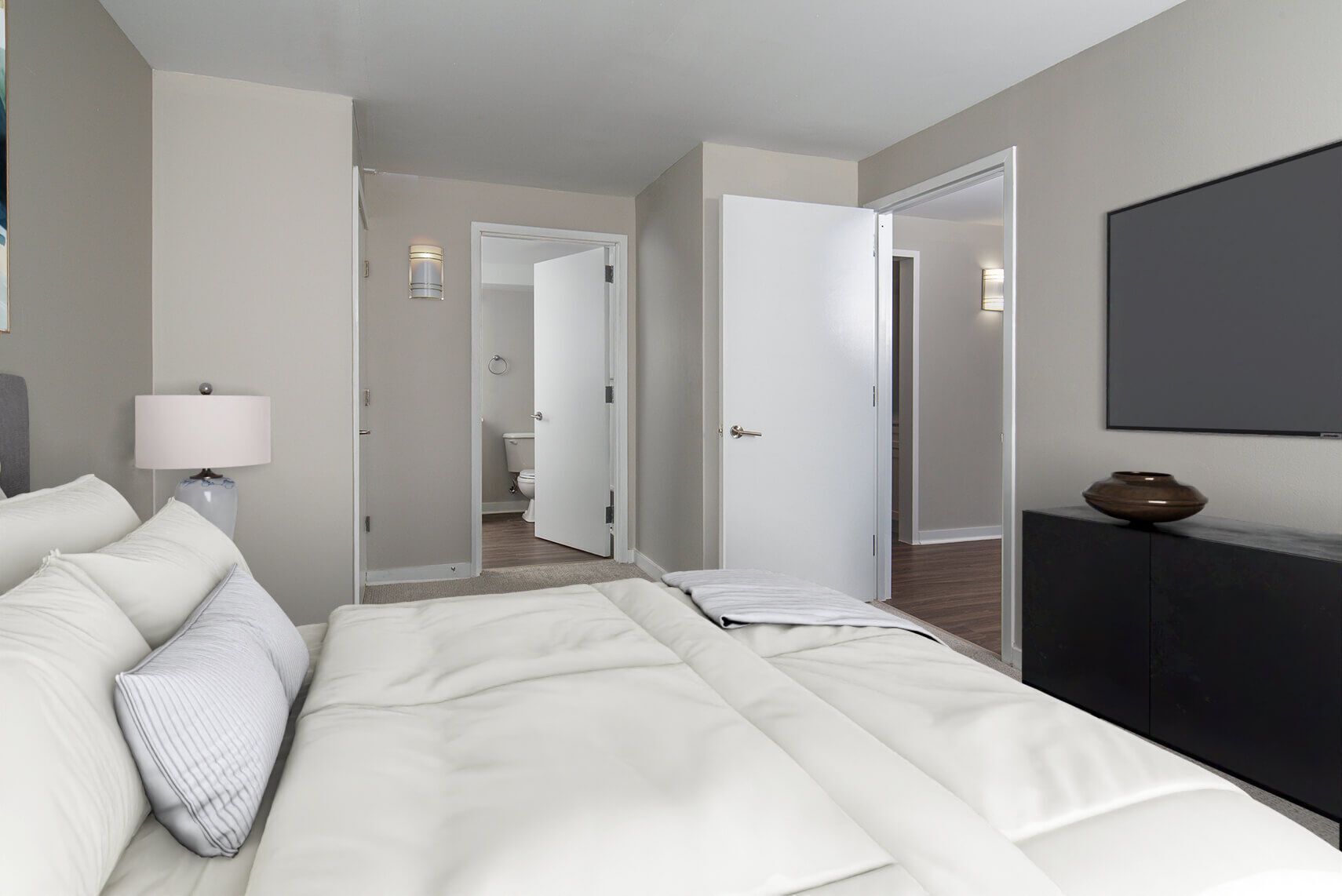 Bedroom with white bedding, gray walls, and three open doors.