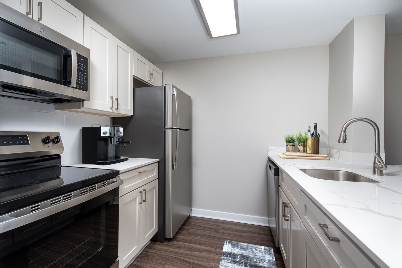 Kitchen with white cabinets, stainless steel appliances, and dark flooring.