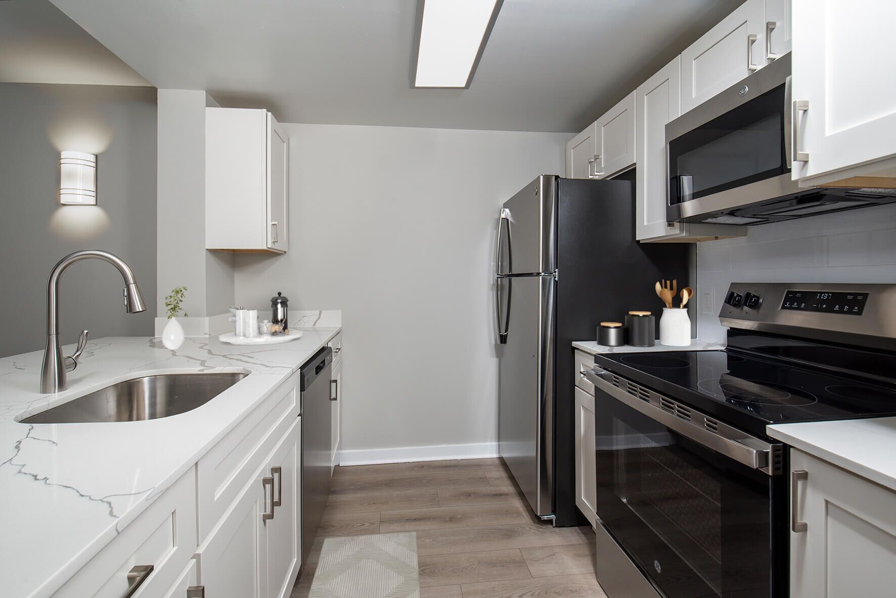 Modern kitchen with white cabinets, stainless steel appliances, and grey walls.