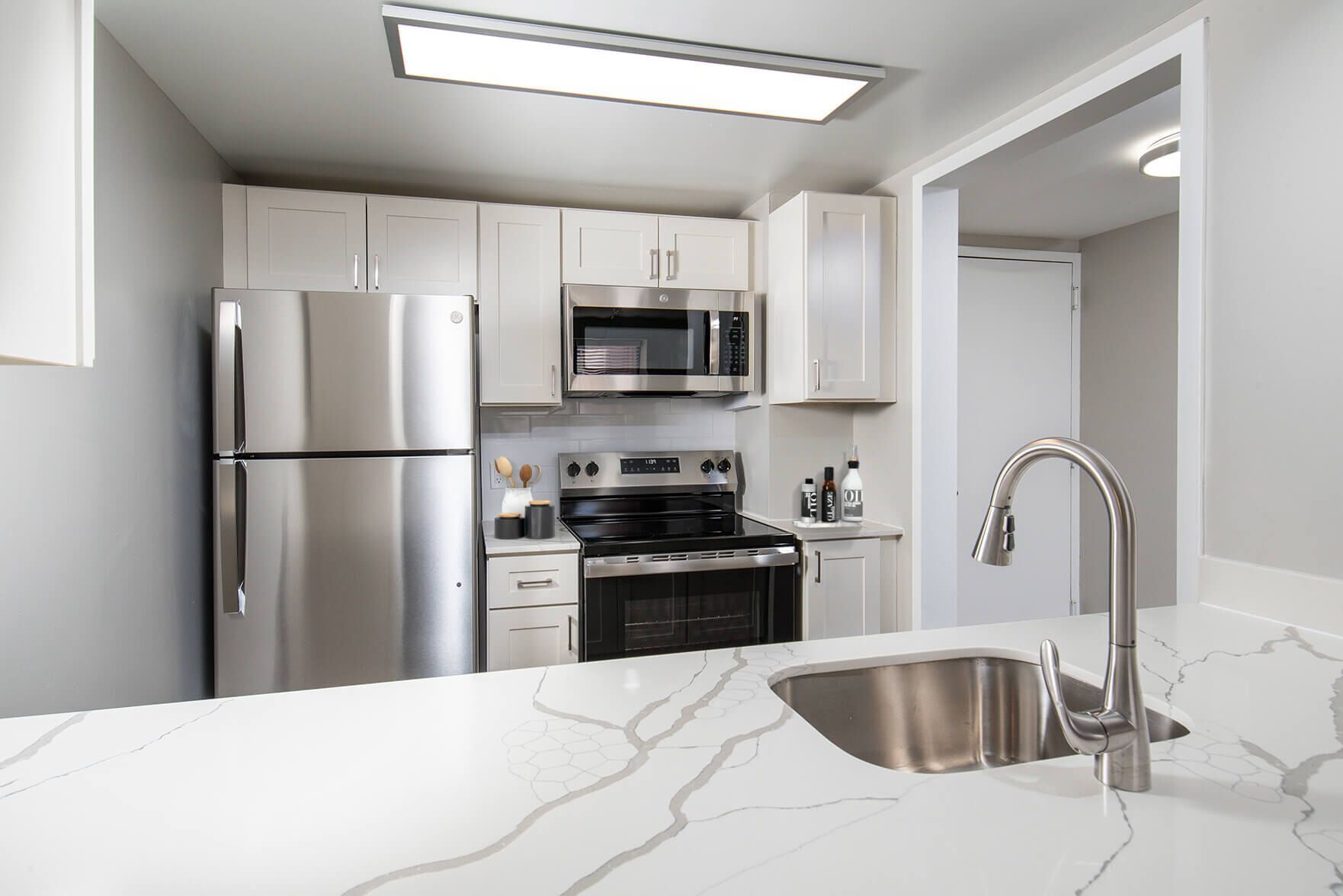 Kitchen with white cabinets, stainless steel appliances, and marble countertop.