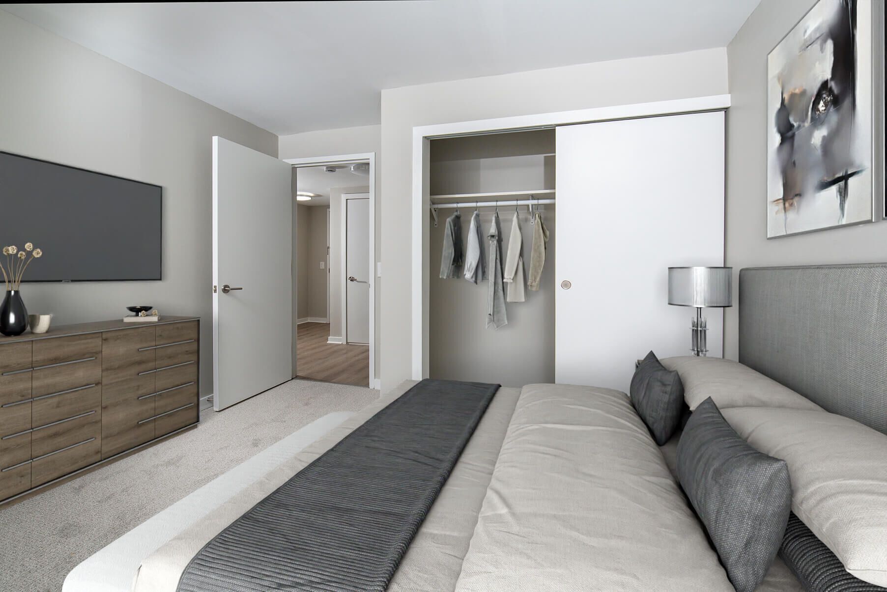 Bedroom with bed, closet, TV, dresser, neutral colors.