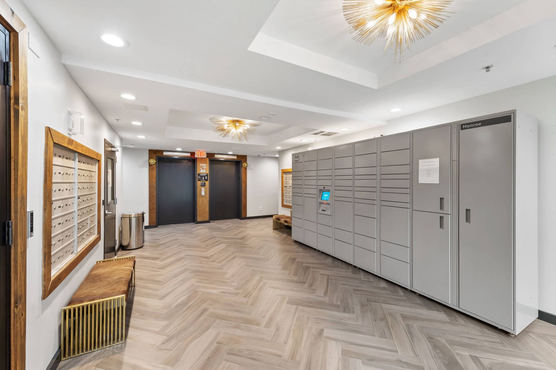 Apartment lobby with mailboxes, lockers, elevators, and decorative lighting. Wooden floors.